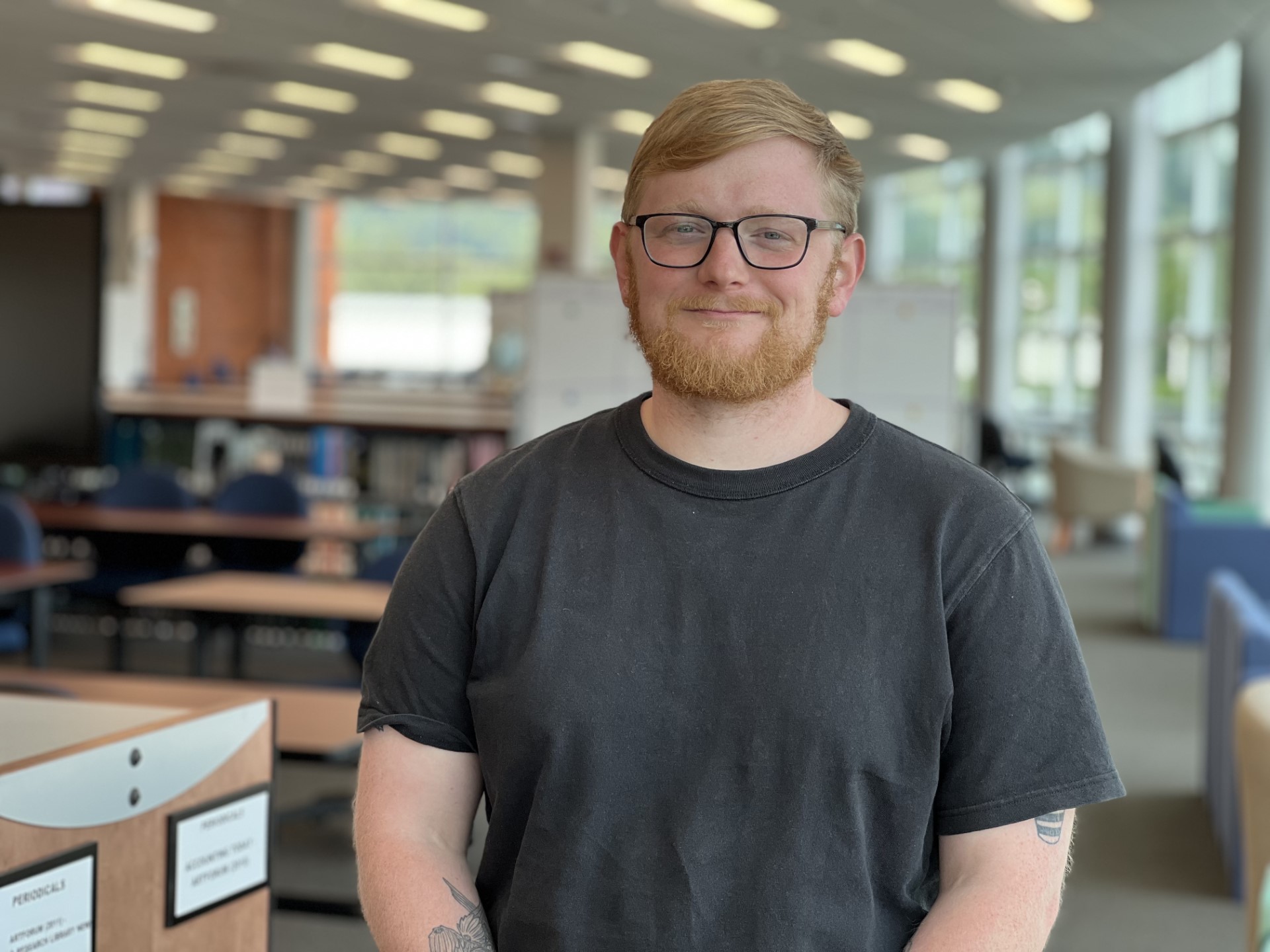 A picture of Ridge Jaco standing in front of book cases on the third floor of Basler Library.