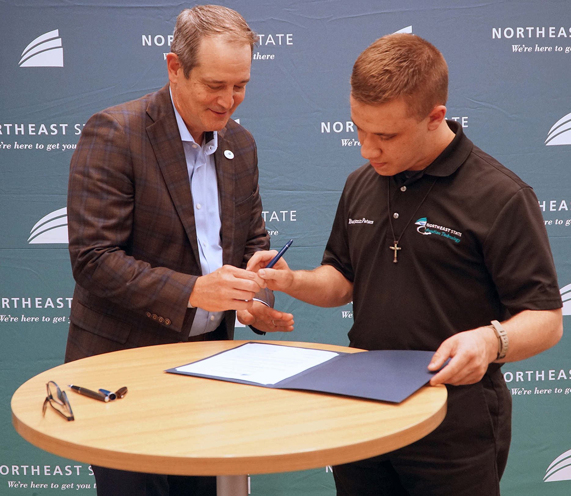 Northeast State President Dr. Jeff McCord hands the pen to student Benjamin Peters who signed his CTE letter of intent with 23 other high school students on April 18.