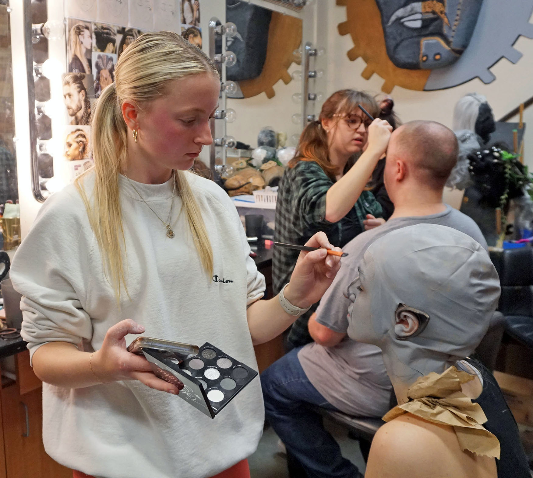 Skye Myers (foreground, left) applies makeup to The Hobbit cast member Tuesday Ingram while Jess Turner (middle, background) does make-up for cast member Connor Mullins.